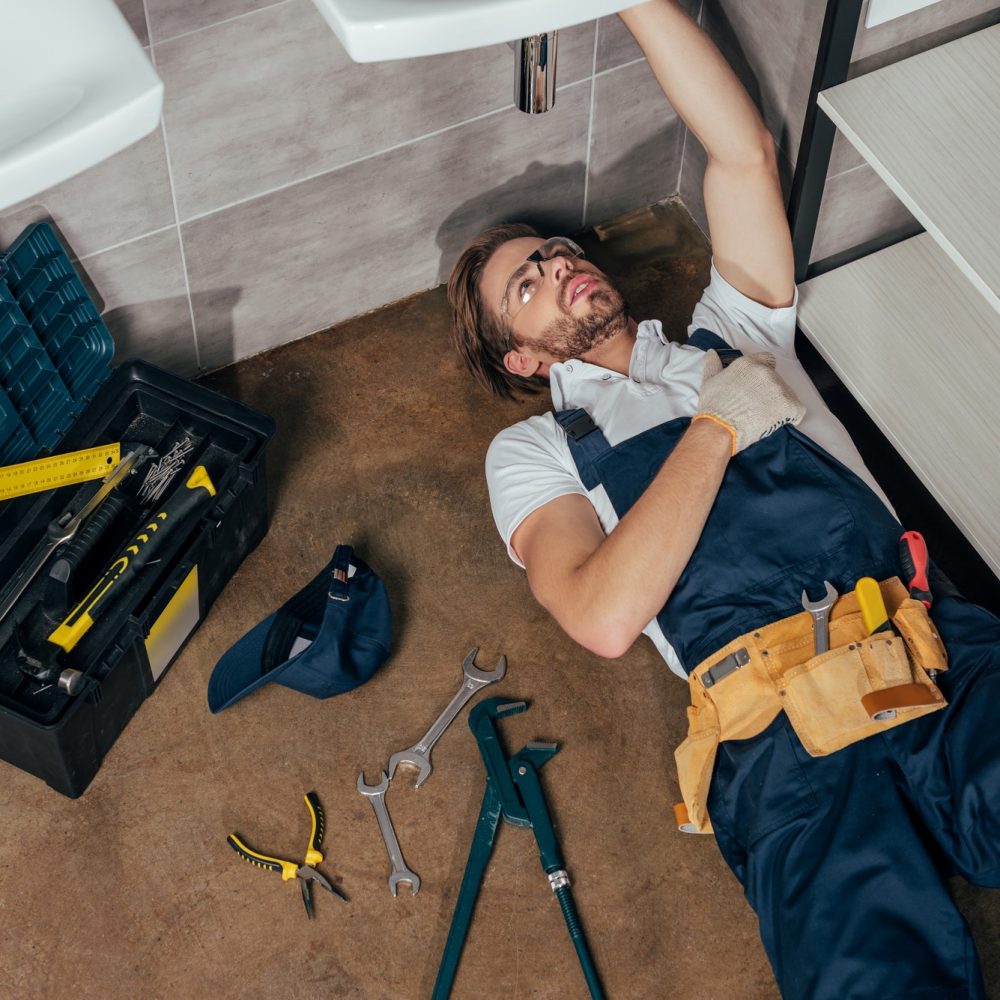 high-angle-view-of-young-male-plumber-fixing-sink-in-bathroom.jpg